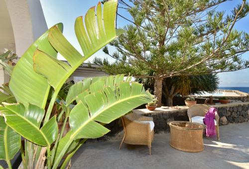 a patio with a table and chairs and a tree at Cossyra Hotel in Pantelleria
