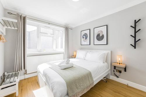 a white bedroom with a white bed and a window at Rose Terrace in London