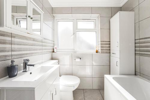 a white bathroom with a toilet and a sink at Rose Terrace in London