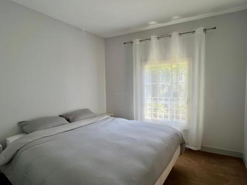ein weißes Schlafzimmer mit einem Bett und einem Fenster in der Unterkunft Spacious & modern flat close to Parc Monceau in Paris