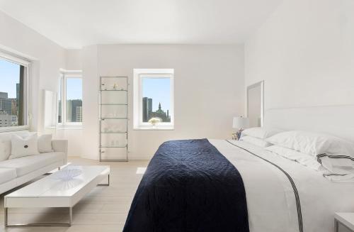 Luxury Midtown West 4 Bedroom Apartment Near Radio City في نيويورك: غرفة نوم بيضاء مع سرير كبير وأريكة