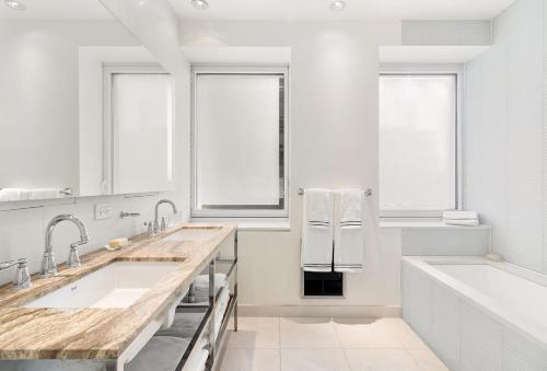 a white bathroom with two sinks and a tub at Luxury Midtown West 4 Bedroom Apartment Near Radio City in New York