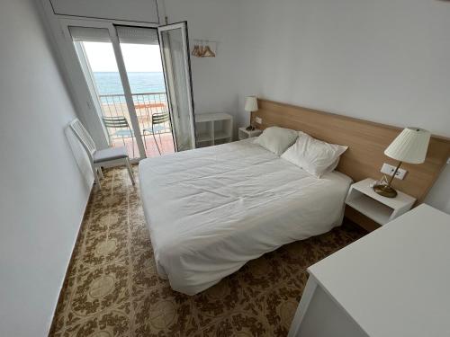 une chambre avec un lit blanc et un balcon dans l'établissement El Llobarret de Baix a Mar, à Torredembarra