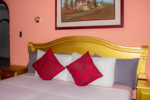 Una cama con dos almohadas rojas encima. en Hotel Raices de la Guajira, en Santa Marta