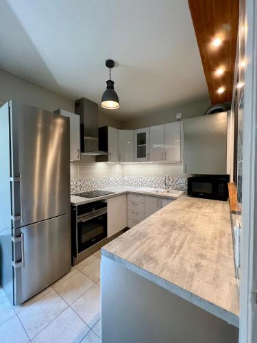 une cuisine avec un réfrigérateur en acier inoxydable et des armoires blanches dans l'établissement Spacious & modern flat close to Parc Monceau, à Paris