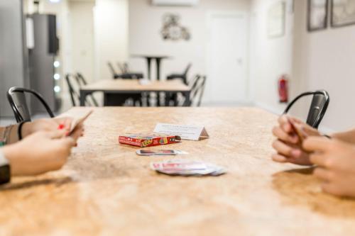 two people sitting at a wooden table with their hands at Piccolo Catalunya Hostel in Alghero