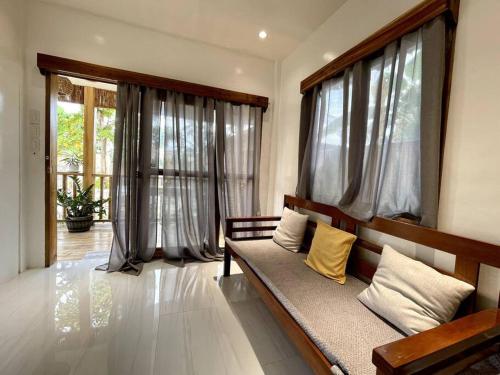 a living room with a bench and large windows at Marhay Villa Siargao in General Luna