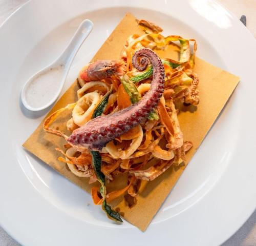 a plate with a pasta dish with sausage and vegetables at Cossyra Hotel in Pantelleria