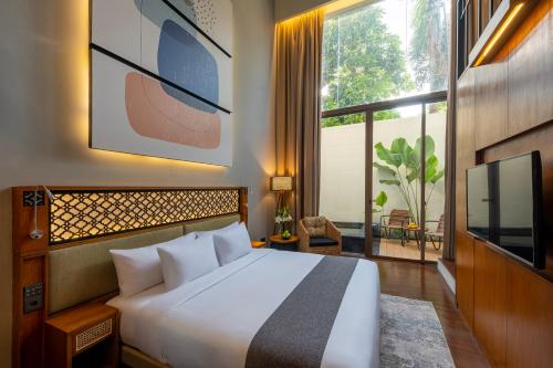 a bedroom with a white bed and a large window at Kayumas Seminyak Resort in Seminyak