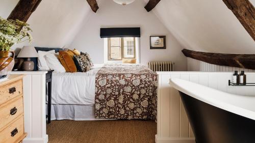 a white bedroom with a bed and a window at Armada Cottage in Charlbury