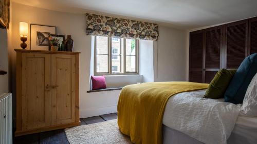 a bedroom with a bed with a yellow blanket and a window at Armada Cottage in Charlbury