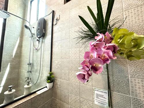 Adagaya Villa Langkawi - Private Pool Villa في بانتايْ سينانج: حمام مع دش مع الزهور على الحائط