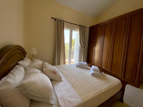 ein Schlafzimmer mit einem Bett mit weißen Kissen und einem Fenster in der Unterkunft Villa Sofia with garden, pool and lounge areas in Kolymbia