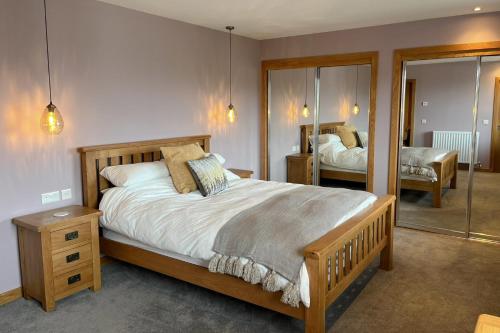 1 dormitorio con 1 cama grande y espejo en Aurora - Self Catering, Kirkwall, Quiet Location with Luxury Hot Tub, en Islas Orcadas
