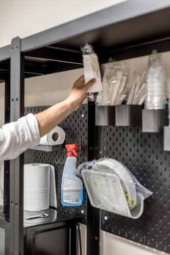 a person is reaching for a shelf in a kitchen at Piccolo Catalunya Hostel in Alghero