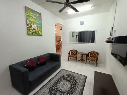 uma sala de estar com um sofá preto e uma ventoinha de tecto em Adempuri homestay em Jitra