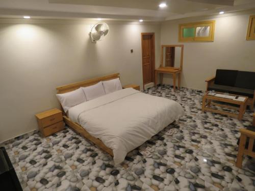 Legendary Hotel Chitral في شيترال: غرفة نوم بسرير ومكتب وتلفزيون