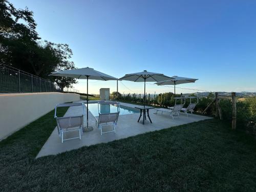 a patio with a table and chairs and umbrellas at Country House "I luoghi dell' anima"con piscina e giardino in Montottone