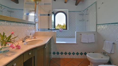 ein Bad mit einem Waschbecken, einem WC und einem Fenster in der Unterkunft VILLA BIDDIZZA 8, Emma Villas in Acireale