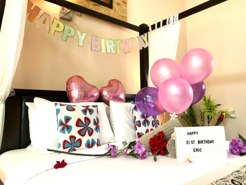 a bed with pink and purple balloons and a happy birthday banner at Adagaya Villa - Villa With Private Pool, Without Pool in Pantai Cenang