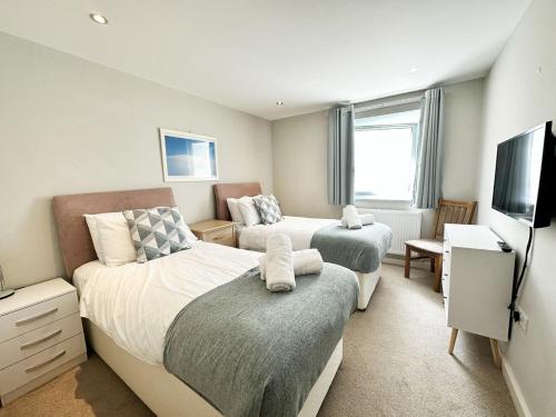 a bedroom with two beds and a flat screen tv at 6 Ocean Views in Newquay