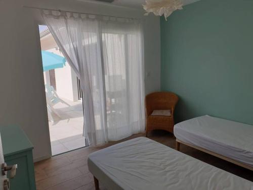 1 dormitorio con 2 camas y ventana con silla en Maison neuve proche du lac de Léon et de l'Océan, en Vielle-Saint-Girons
