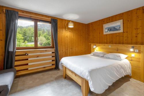 レ・ズッシュにあるFontaine du Mont Blanc Hotel & Spaの木製の壁のベッドルーム1室、窓付きのベッド1台が備わります。