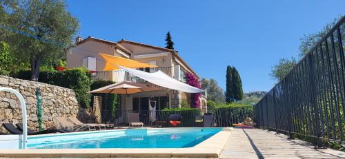 a swimming pool with an umbrella and a house at "La Colombe sous les Oliviers" Gîte jusqu'à 4 personnes - 75m2 - Sur Boooking - Rez de jardin Piscine Vue mer et lac in Spéracèdes