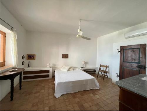 a white bedroom with a bed and a table and a desk at Casa Rosa - Santa Marina in Santa Marina Salina