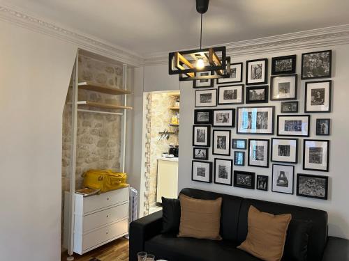 un salon avec un canapé noir et un mur de photos dans l'établissement Cosy appartement à 500m de Montmartre, à Paris