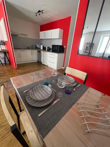 a dining room table with plates and a red wall at En Salvy : hyper centre + parking gratuit in Albi