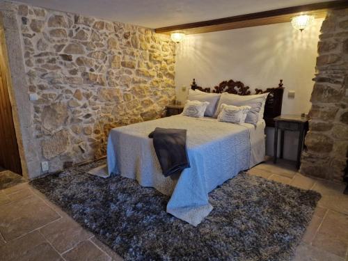 a bedroom with a bed with a stone wall at Casarão do Largo da Eira in Tomar