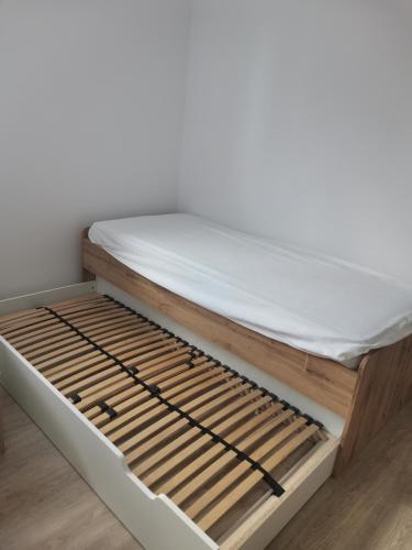 uma cama com uma estrutura de madeira e lençóis brancos em Casa Mariș em Cluj-Napoca