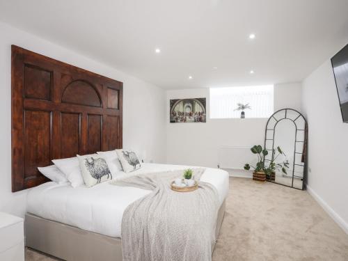 a white bedroom with a large bed and a table at The School House in Holyhead