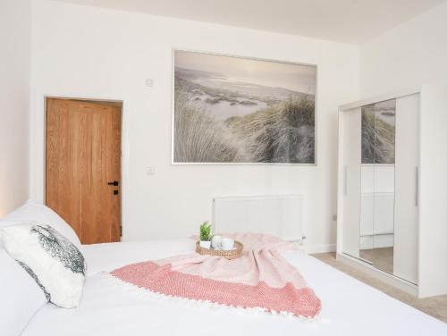 a white bedroom with a bed with a pink blanket at The School House in Holyhead