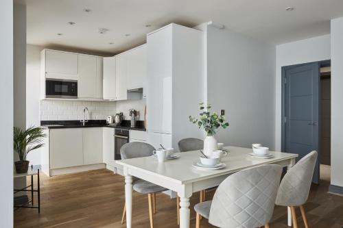 a kitchen and dining room with a white table and chairs at Ealing Broadway by Viridian Apartments in Ealing