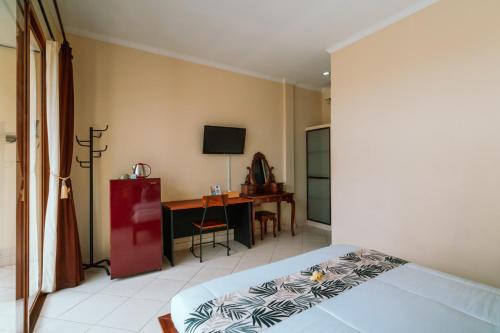 a bedroom with a bed and a desk and a television at Umah Kita in Seminyak
