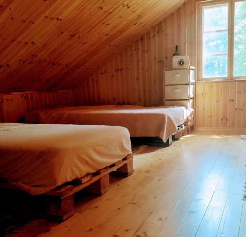 1 dormitorio con 2 camas en una cabaña de madera en Lakefront Log House and Sauna, en Ginučiai