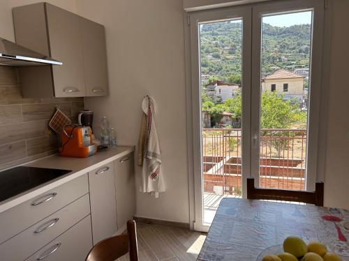 eine Küche mit einem Tisch und Blick auf einen Balkon in der Unterkunft Casa Marisa in Camporosso