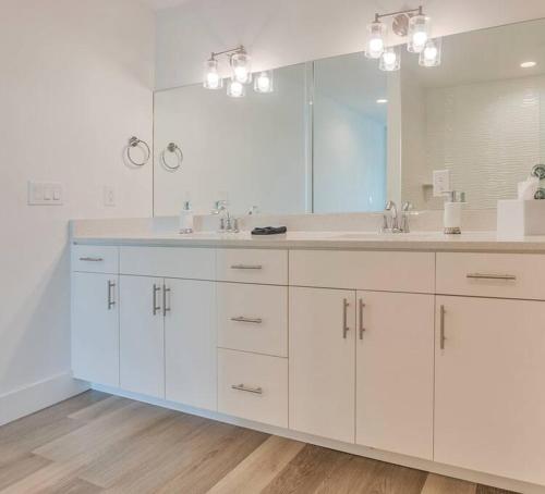 a bathroom with two sinks and a large mirror at New Luxury Condo w/ Heated Pool 1 Block From Gulf in St. Pete Beach