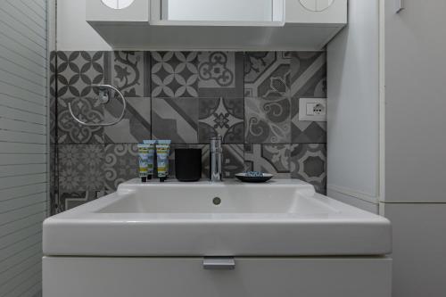 lavabo blanco en un baño blanco con azulejos en Espinasse Apartment, en Milán