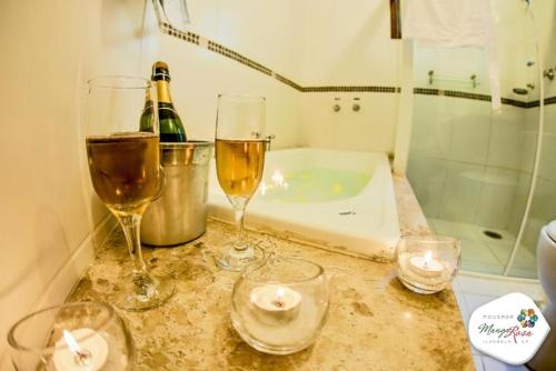 dos copas de vino sentadas en un mostrador en un baño en Pousada Manga Rosa, en Ilhabela