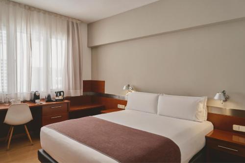 a hotel room with a large bed and a desk at Tres Torres Atiram Hotels in Barcelona