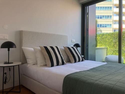 ein Schlafzimmer mit einem Bett mit Kissen und einem Fenster in der Unterkunft Oasis 28 by Innkeeper in Lissabon