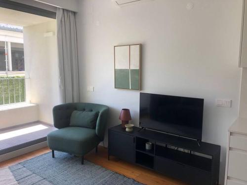 ein Wohnzimmer mit einem grünen Stuhl und einem TV in der Unterkunft Oasis 28 by Innkeeper in Lissabon