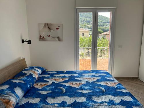ein Schlafzimmer mit einem Bett mit blauer Decke und einem Fenster in der Unterkunft Casa Marisa in Camporosso