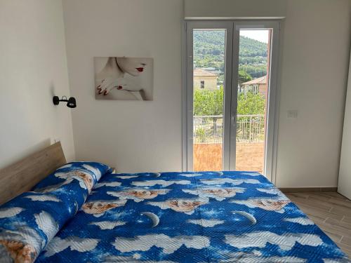 a bedroom with a bed with a blue comforter and a window at Casa Marisa in Camporosso