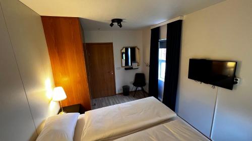 a bedroom with a bed and a flat screen tv at Westfjords - Rooms in Bolungarvík