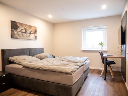 a bedroom with a bed and a desk and a window at Pension HSL in Graben-Neudorf