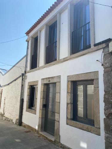 a white building with black windows on a street at CASA BAIONA CENTRO in Baiona